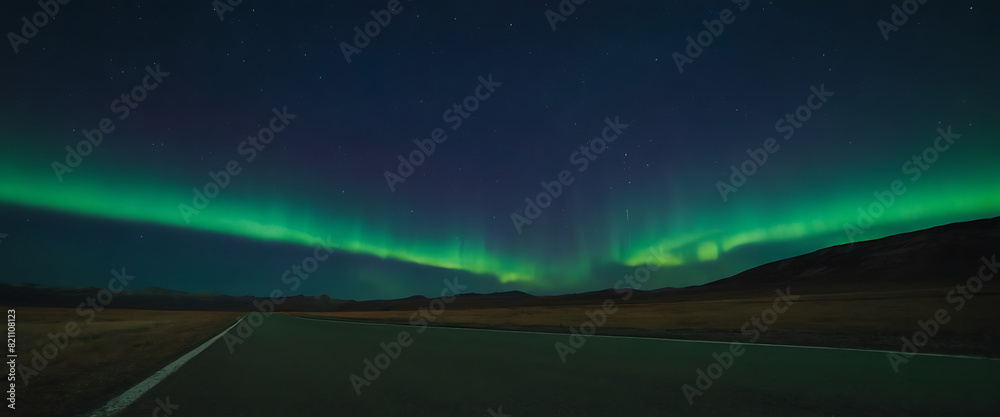 A vibrant green aurora borealis dances across a dark sky, illuminating a lonesome road stretching towards the horizon.