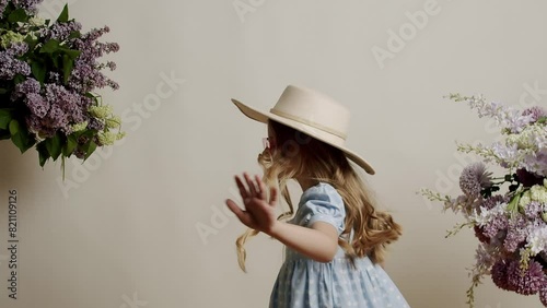 The 7-year-old little girl in a light blue dress with a white hat and sunglases it revolves around it and is positive on a white background in the studio. Little Blonde Cute Girl Face. photo