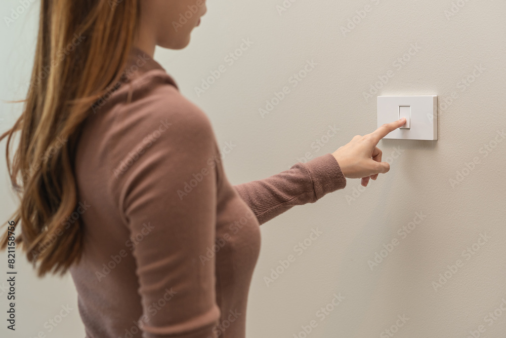Asian young woman hand turn off on lighting switch at home room. Finger ...