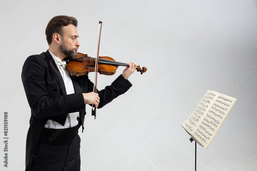 Man violinist with beard playing violin while facing sheet of music Man violinist with beard playing violin while facing sheet of music
