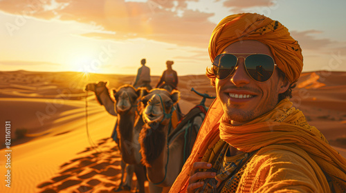 a man in a yellow headscarf, sunglasses, and a big smile, leading a group on a camel trek across dunes, the sun high in the sky.