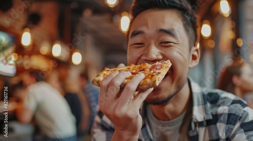 Hungry Asian man eats pizza in the bar/restaurant with friends and colleagues.