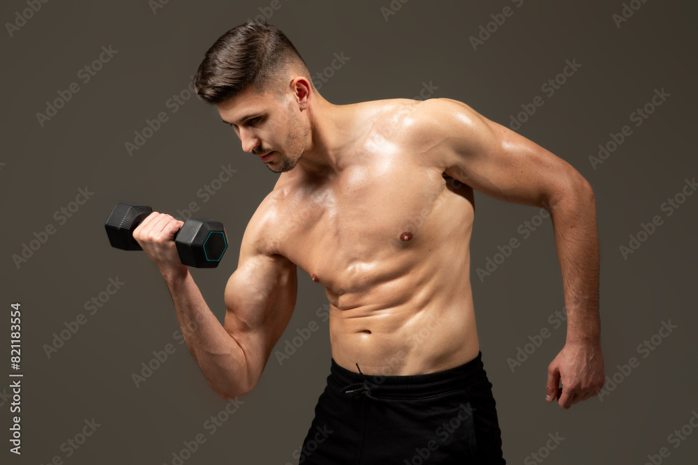 A man is lifting a dumbbell in front of a plain gray background. He is focused and determined, showcasing strength and fitness. A man is lifting a dumbbell in front of a plain gray background. He is focused and determined, showcasing strength and fitness.