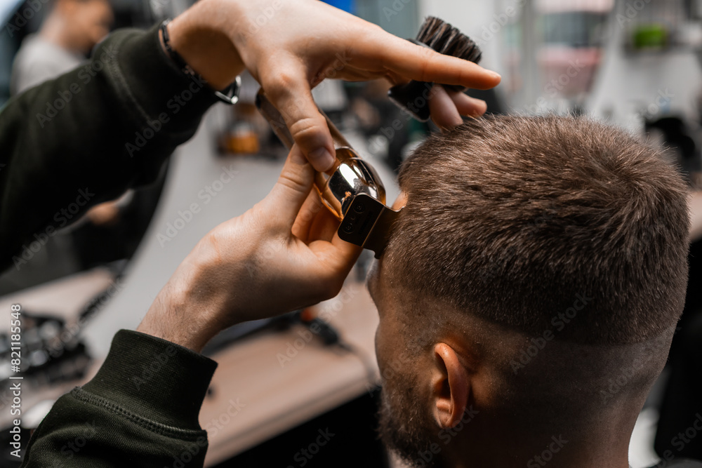 Barber shaves the clients hair with an electric trimmer in the modern barbershop. 