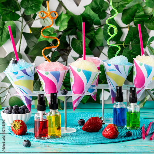Several fruit flavoured snow cones with crazy straws and flavoured syrup.