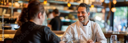 Handsome male chef in white uniform talking with a customer at a restaurant, exemplifying good service