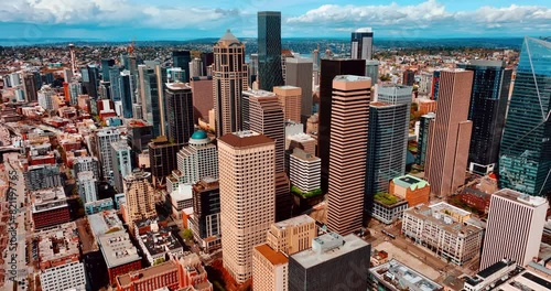 Flying closer to the beautiful modern high-rise buildings in the downtown of Seattle, Washington, US. Sunny cityscape of the metropolis from top. photo