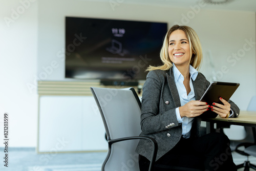 Professional woman working with tablet in bright, modern office during daytime meeting