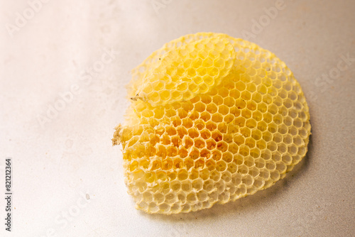 A yellow honeycomb filled with honey on a wall background. © Kanthita