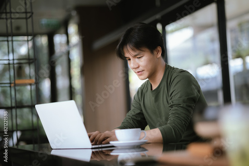 A young Asian man works at a coffee shop during the weekend.