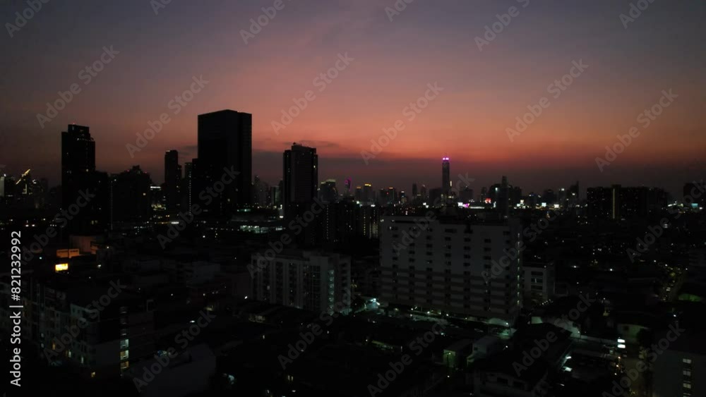 night illumination of Bangkok at sunset with orange sky and dark buildings night illumination of Bangkok at sunset with orange sky and dark buildings