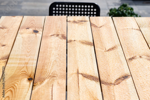 A modern table made of raw wood covered with yacht varnish, standing on the garden terrace.