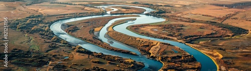 Aerial view of a meandering river cutting through a vast, arid landscape, showcasing natural beauty and geographical formations.