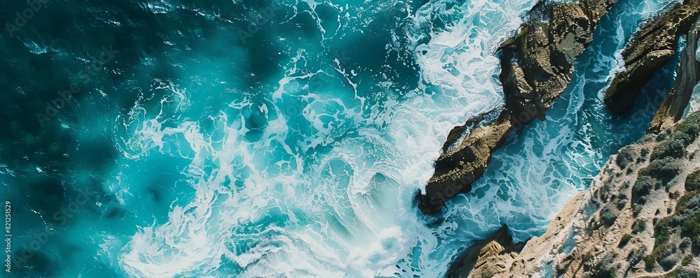 Aerial view of turquoise waves crashing onto rocky cliffs. Stunning coastal landscape with rugged shoreline and powerful ocean waves. Aerial view of turquoise waves crashing onto rocky cliffs. Stunning coastal landscape with rugged shoreline and powerful ocean waves.