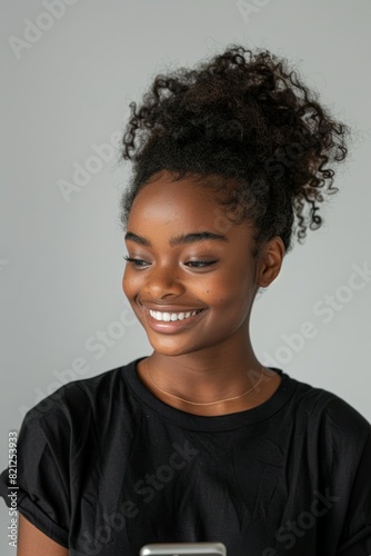 A woman with curly hair is smiling and holding a cell phone