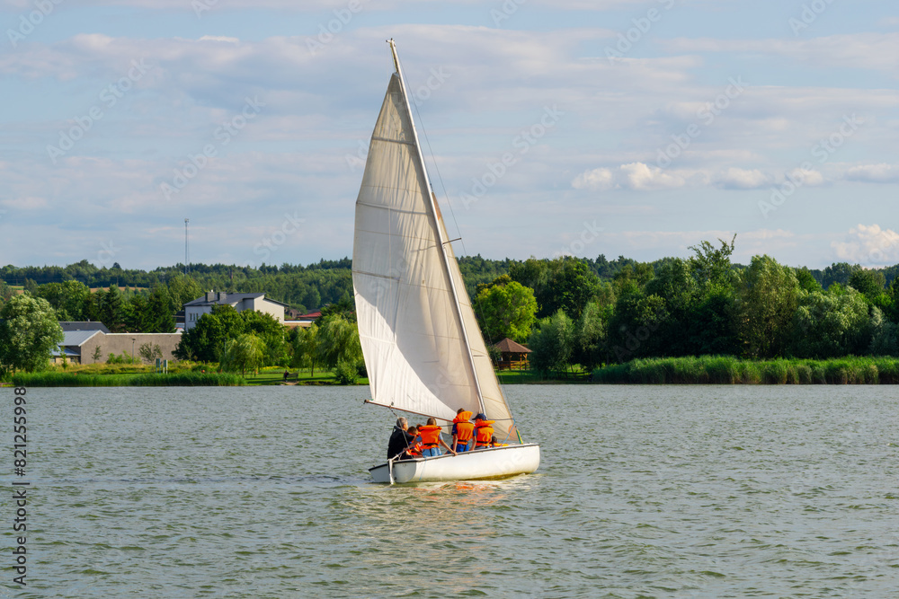 A sailboat with a white sail is sailing on a lake