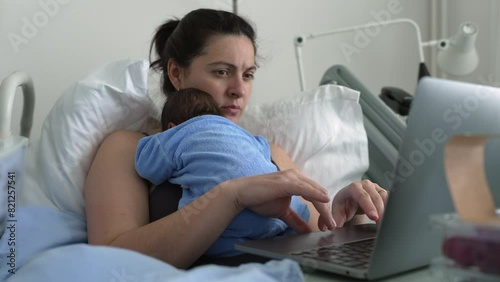 New mother multitasking in hospital bed with newborn baby, working on laptop, combining parenting and remote work, healthcare and technology, postnatal care, family bonding photo