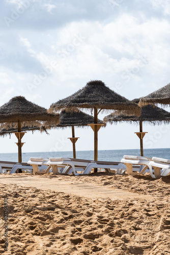 Straw chairs and umbrella. Praia do Peneco beach  Albufeira  Algarve  Portugal. Praia dos Pescadores beach. Fishermen  sunny day