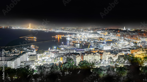 Algiers, Algeria- April 19, 2024: aerial view on the capital city by night sea bay and pier port, Mediterranean sea water ships and boats. The Great mosque and the Martyr's Memorial monument.