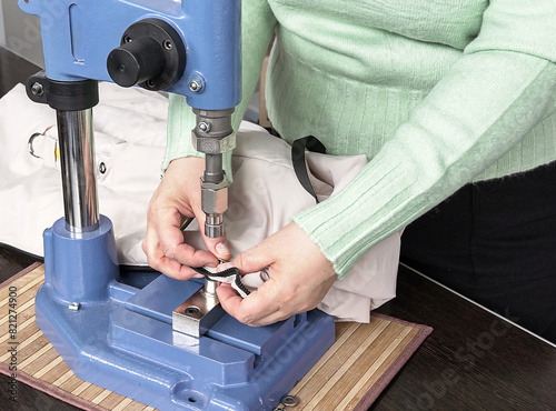in a sewing workshop close-up of female hands and a riveting machine on fabric. photo