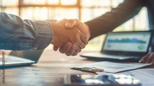 Two People Shaking Hands in Front of Laptops