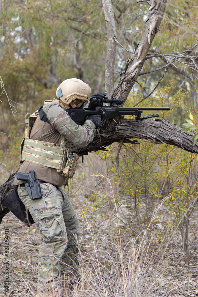 Naklejka premium Soldier airsoft player dressed in camouflage uniform wielding a sniper rifle