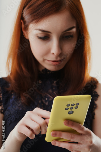 Woman intently examines yellow smartphone with many cameras