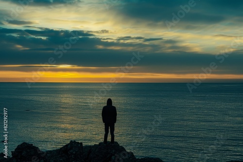 Silhouette of a Person Standing by the Ocean at Sunset
