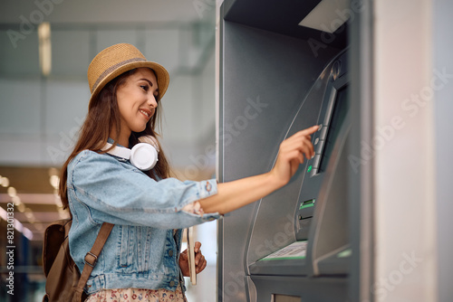 Cuadro en lienzo Young woman using ATM at airport.