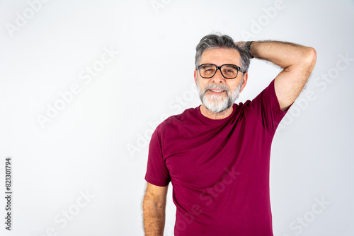 Happy, satisfied mature man runs hand through healthy hair after haircut in front of isolated background.
