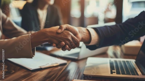 Two People Shaking Hands in Front of Laptops