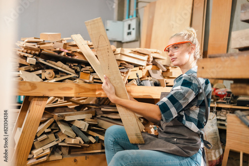 Attractive middle aged woman carpenter designer works with ruler, make notches on the tree in workshop. Image of modern femininity. Concept of professionally motivated women