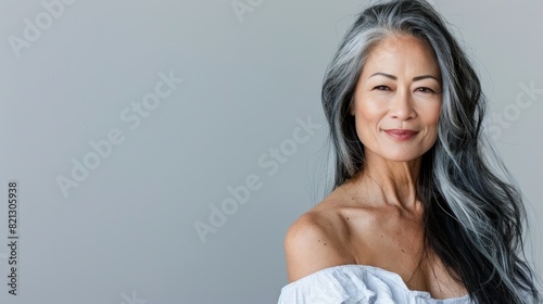 A woman with grey hair and a white top stands in quiet contemplation