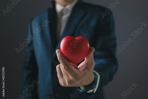 Businessman in suit holding red heart, healthcare, giving love, valentine and love festival concept.