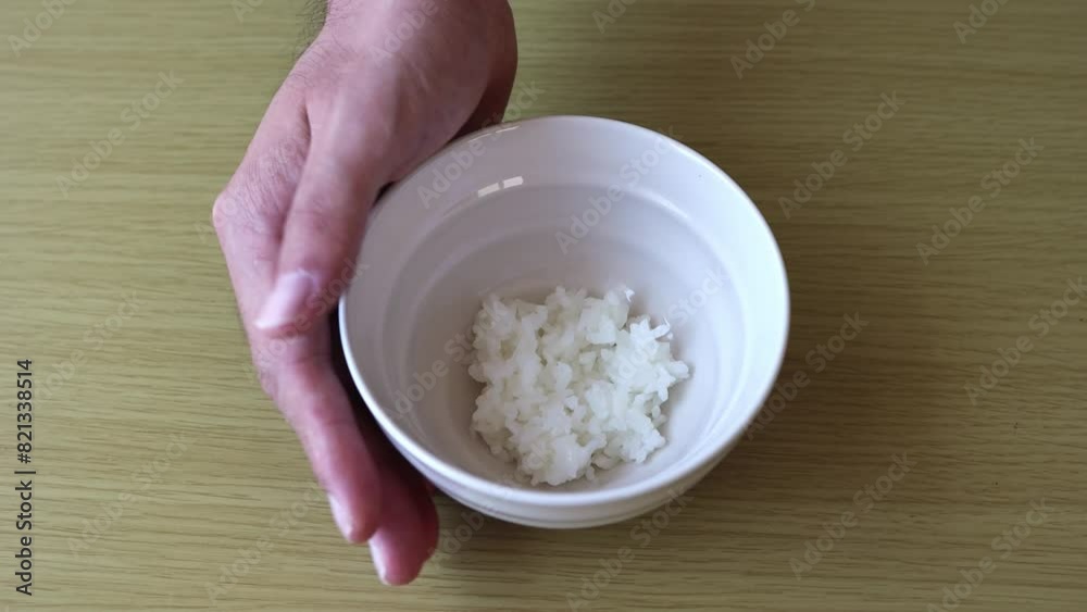 茶碗に入れた少しのご飯を出す男性の手。貧困のイメージ 茶碗に入れた少しのご飯を出す男性の手。貧困のイメージ