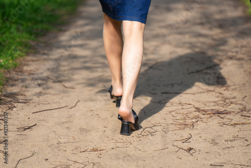 A woman's feet with the heels of her sandals slipped off