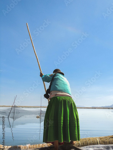 A Peruvian woman standing on a boat fishing with a pole on Lake Titikaka. photo