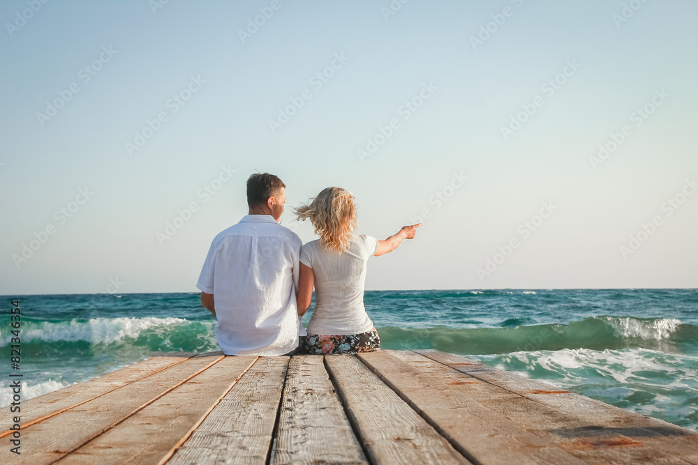A happy couple walking along the pier by the sea in the nature of travel