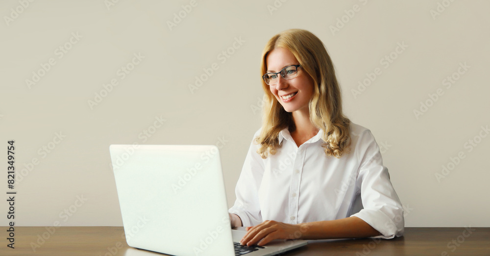Happy woman working with laptop sitting at desk in office or home Happy woman working with laptop sitting at desk in office or home