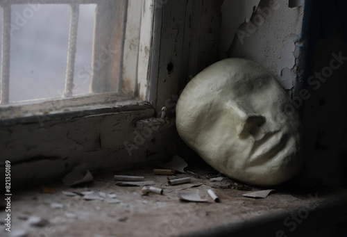an abstract image with a theatrical mask at a window in an abandoned building