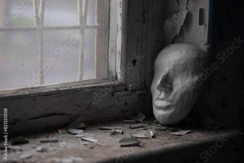 an abstract image with a theatrical mask at a window in an abandoned building