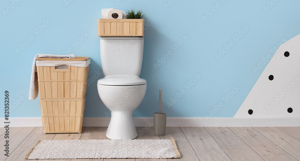 Interior of restroom with toilet bowl and baskets near blue wall. Banner for design Interior of restroom with toilet bowl and baskets near blue wall. Banner for design