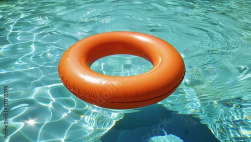 Photo of an orange inflatable ring floating on the water surface, with clear and clean blue-green pool water