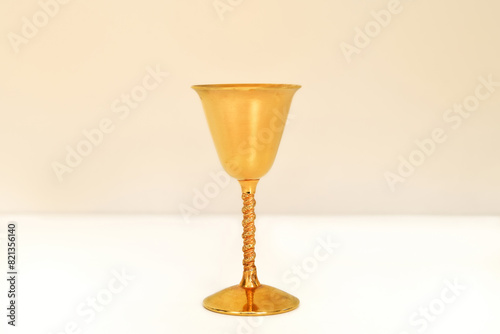 Golden antique goblet with high stem on the white table. Close-up. Copy space.


