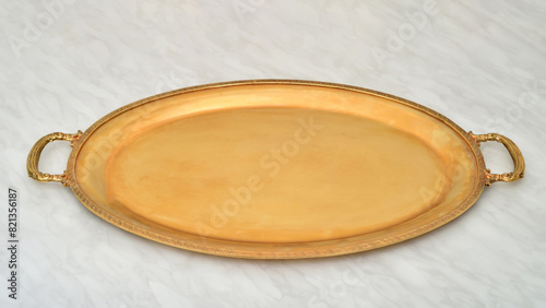 Golden antique tray on the light gray marble table texture. Selective focus.

