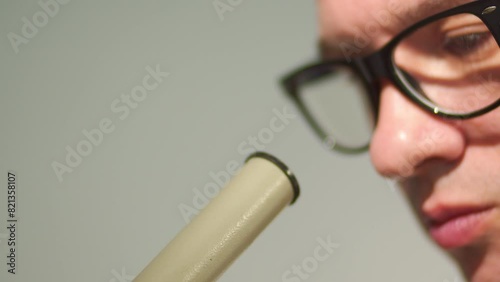 Close up portrait Pensive Male researcher leans towards the microscope eyepiece