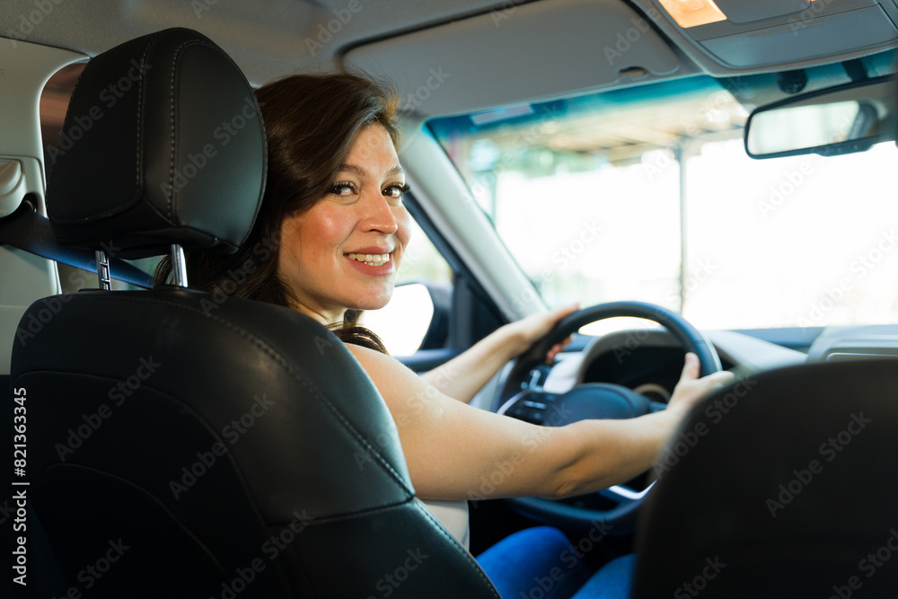 Confident woman driving with a smile, hands on steering wheel in modern vehicle, exuding independence and happiness on her commute