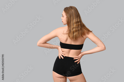 Pretty young woman in black underwear on light background, back view © Pixel-Shot