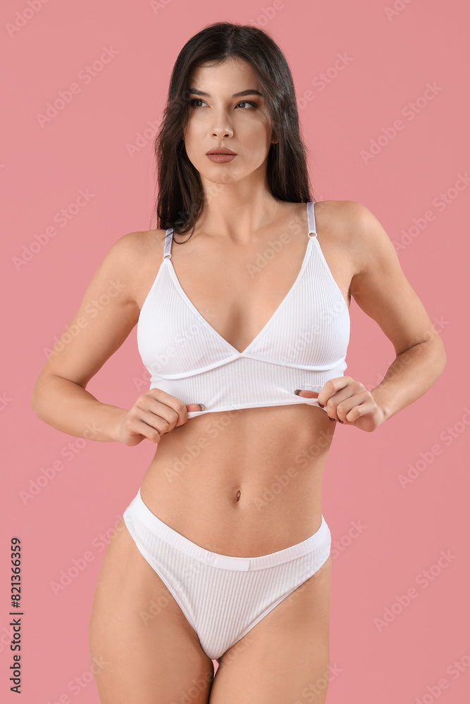 Fototapeta premium Pretty young woman in white underwear on pink background