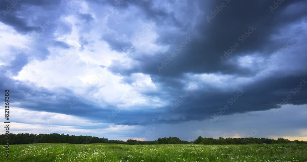 A stormy sky hangs over a grassy field with trees in the backdrop A stormy sky hangs over a grassy field with trees in the backdrop